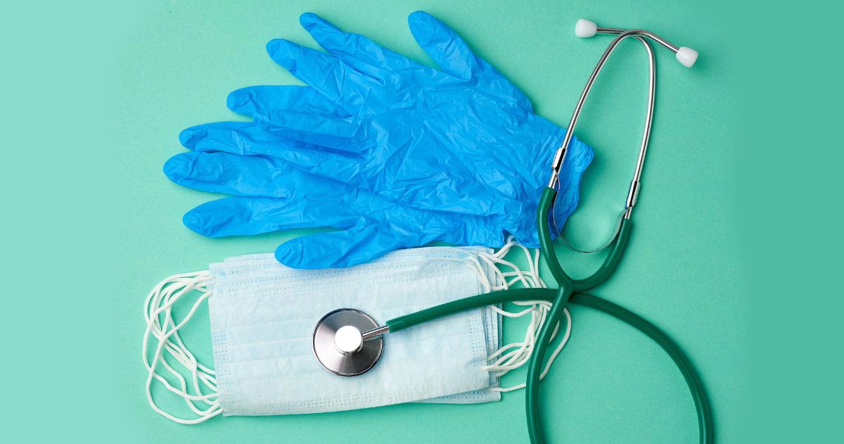 Material de Enfermagem - Luvas de látex azuis e máscaras descartáveis em um fundo verde