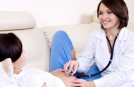 Técnico em enfermagem avaliando batimento cardíaco do bebê na barriga da mãe - Especialização em Obstetrícia para Técnicos em Enfermagem