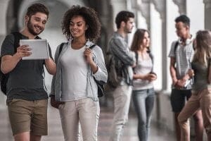 estudantes reunídos olhando para um tablet em ambiente escolar - Conciliar Trabalho e Estudo