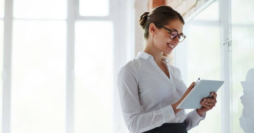 Professora em sala de aula em frente a quadro branco - vantagens de fazer um curso técnico presencial