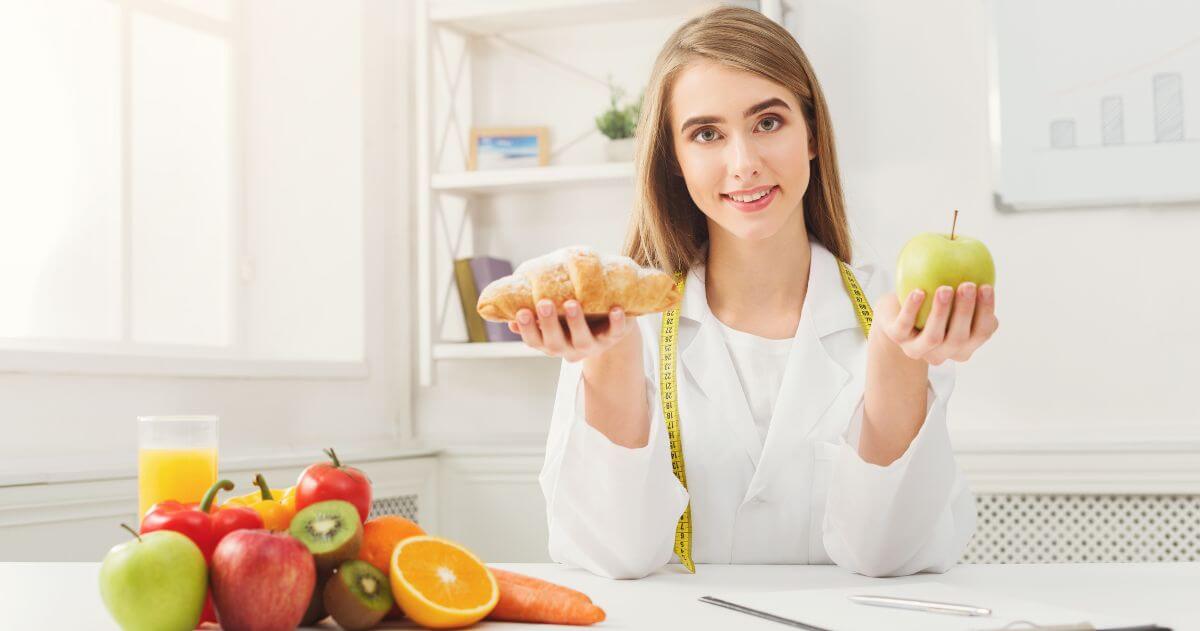 Nutricionista segurando uma fruta e um pão - o que você aprende no Curso de Nutrição