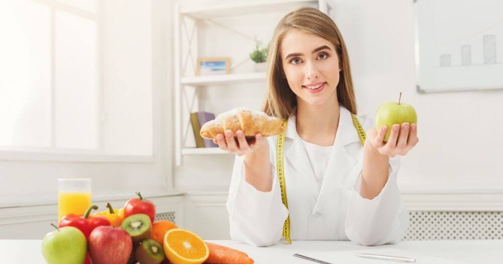 Nutricionista segurando uma fruta e um pão - o que você aprende no Curso de Nutrição