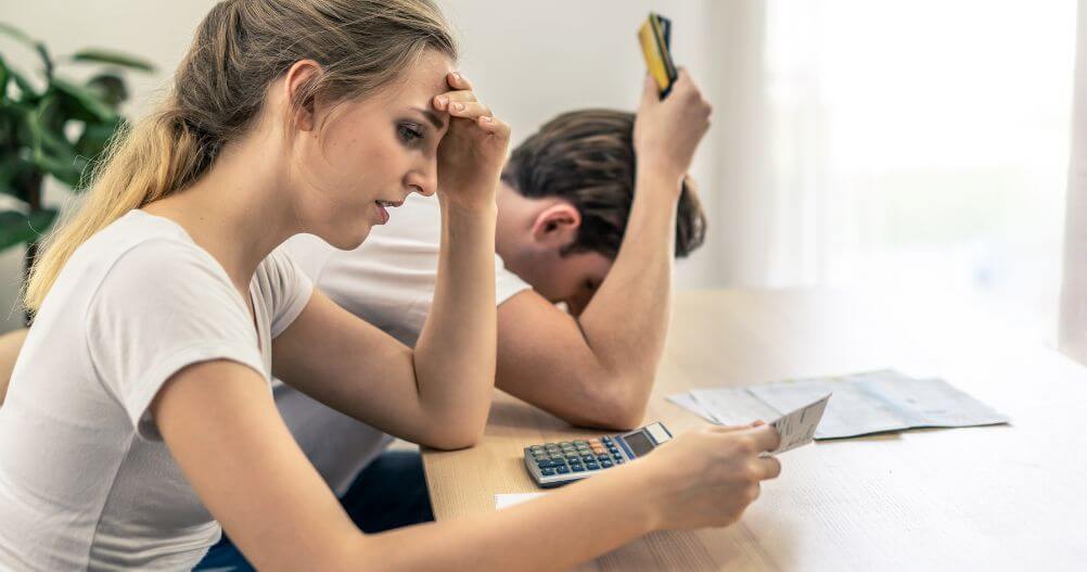 jovem casal com dificuldades financeiras - principais causas do desemprego e como evitá-las