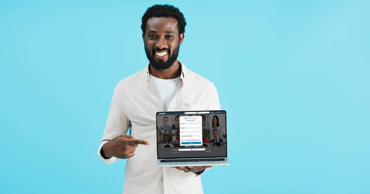 Homem negro apontando para laptop com página do LinkedIn - LinkedIn para conseguir um novo emprego