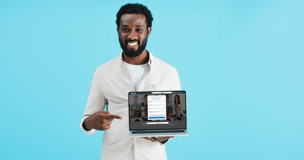 Homem negro apontando para laptop com página do LinkedIn - LinkedIn para conseguir um novo emprego