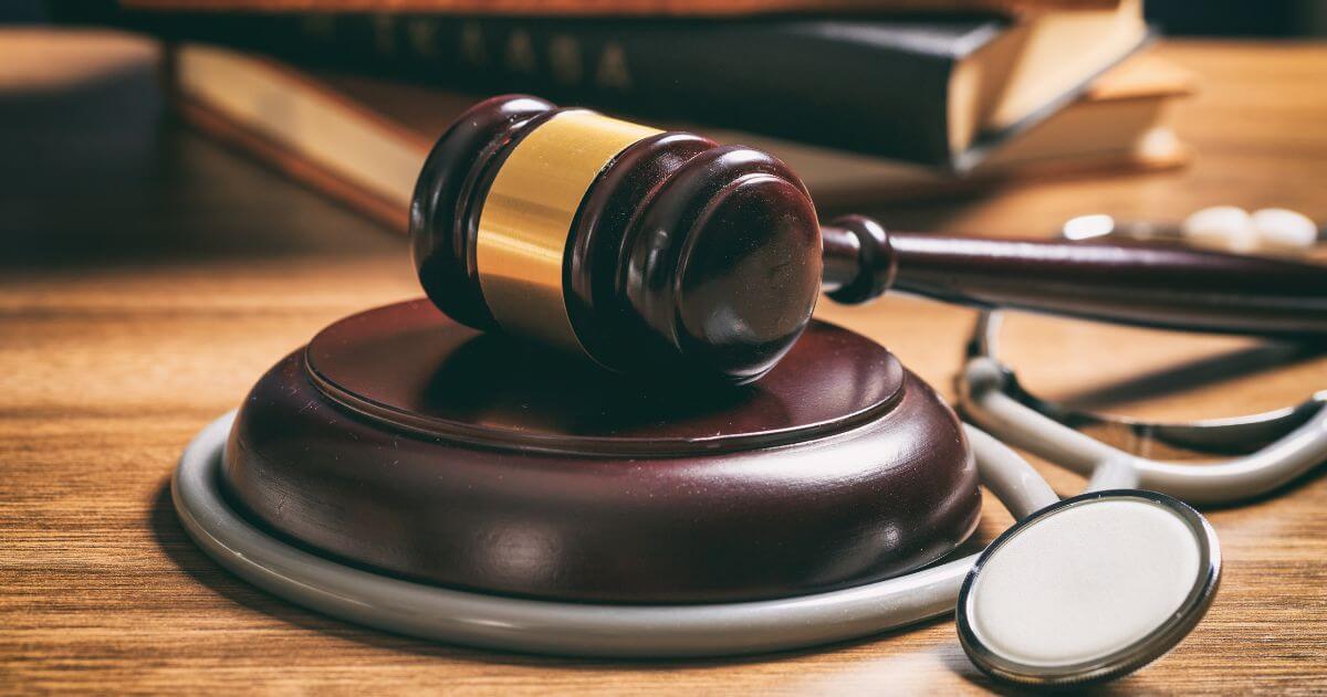 Juiz martelo e um estetoscópio em uma mesa de madeira - Piso da Enfermagem foi suspenso pelo STF; entenda o caso