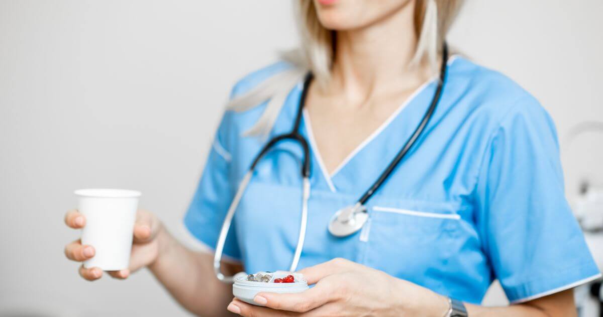 Enfermeira com caixa de remédios e um copo de água - Principais Competências do Técnico em Enfermagem