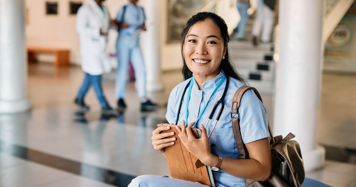 Estágio de Técnico em Enfermagem - Feliz estudante asiática de enfermagem na entrada do hospital olhando para a câmera.