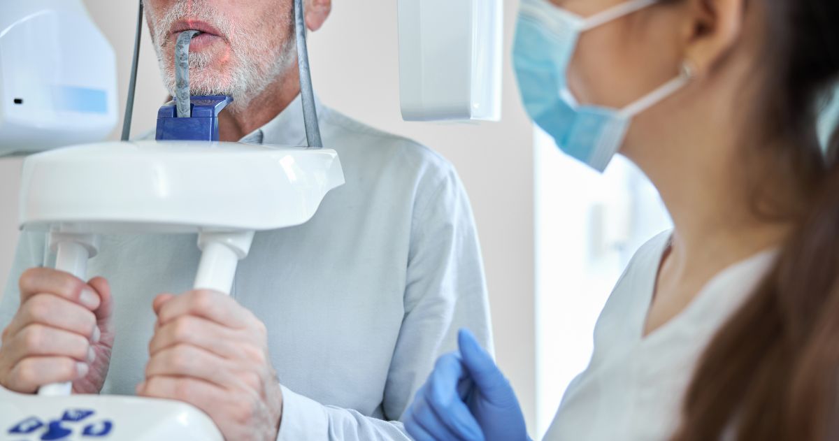 Técnico em Radiologia preparando um homem idoso para radiografia dentária - Radiologia Odontológica