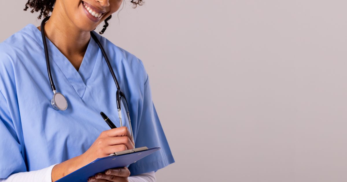 Técnico ou Auxiliar de Enfermagem: qual a melhor opção? - Técnica em Enfermagem com estetoscópio escrevendo na área de transferência
