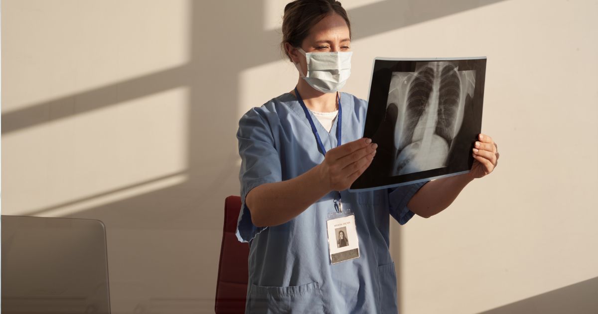 Duração do Curso Técnico em Radiologia - Jovem técnico em radiologia séria olhando a imagem de raio-x no consultório médico