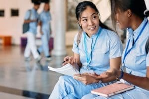 Especialização Técnica - Estudante asiática de enfermagem e sua amiga conversando enquanto estudavam no corredor da universidade médica.