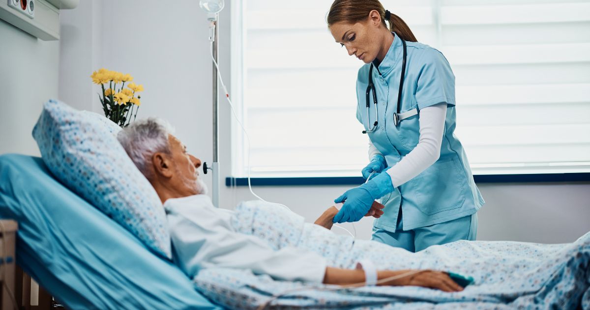 vantagens de fazer um Curso Técnico em Enfermagem - Enfermeira adulta média verificando gotejamento intravenoso de paciente sênior na enfermaria do hospital.
