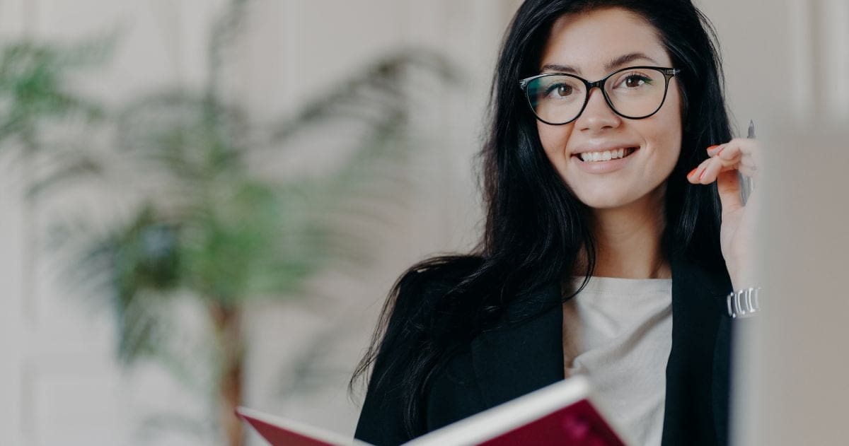 Curso Livre - estudante segura o bloco de notas e a caneta, faz anotações, gasta tempo livre para pesquisas.